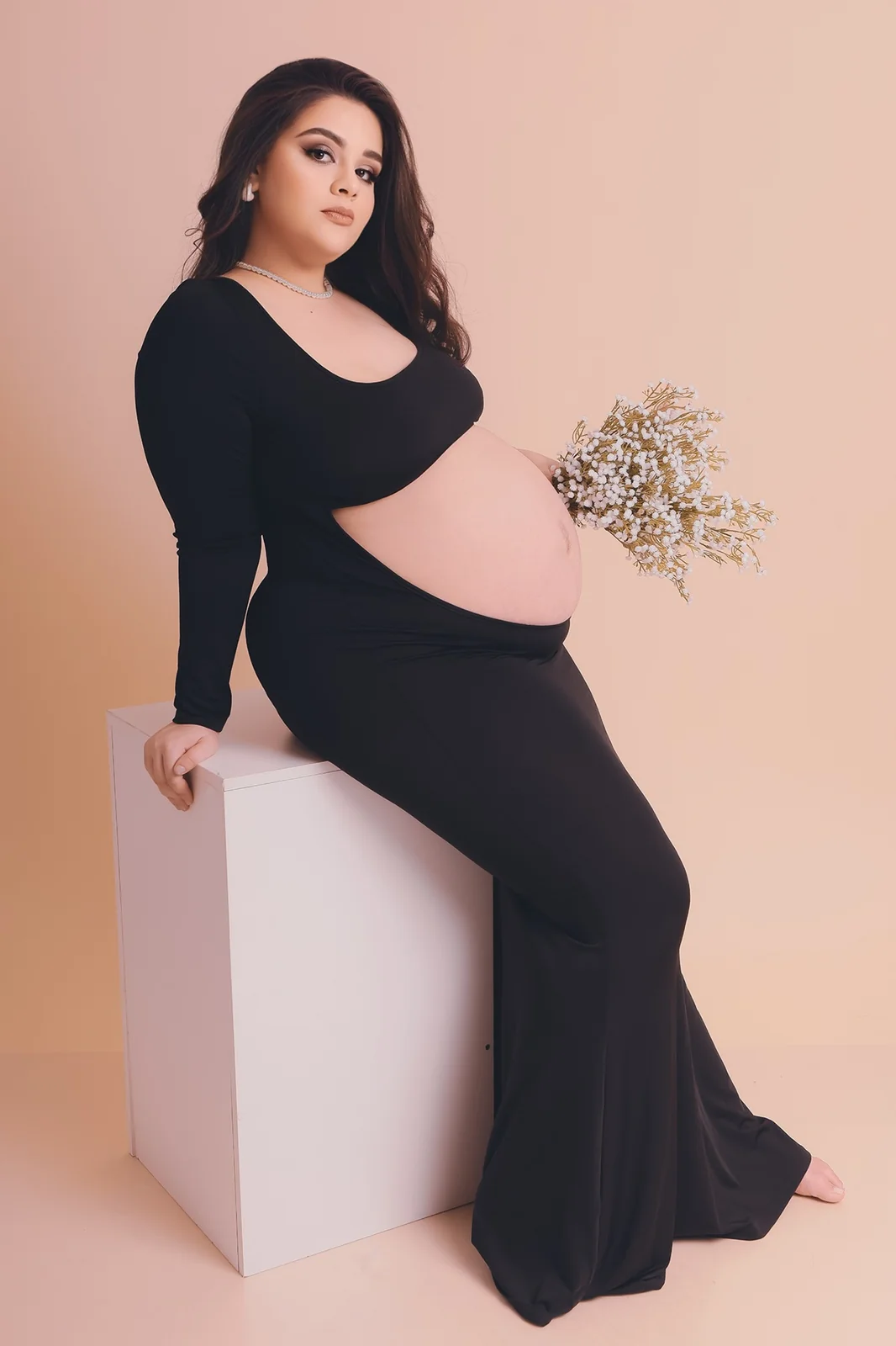 Retrato de gestante sentada em estúdio com estética sofisticada
