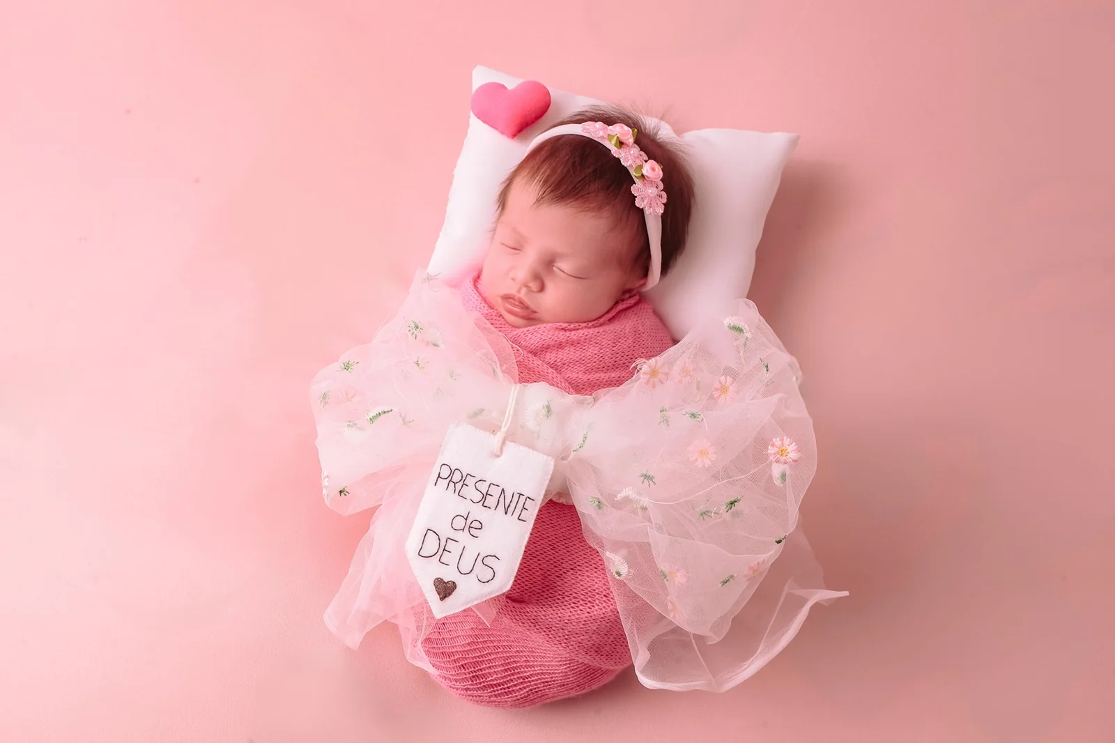 Fotografia newborn de bebê em cenário rosa com produção delicada