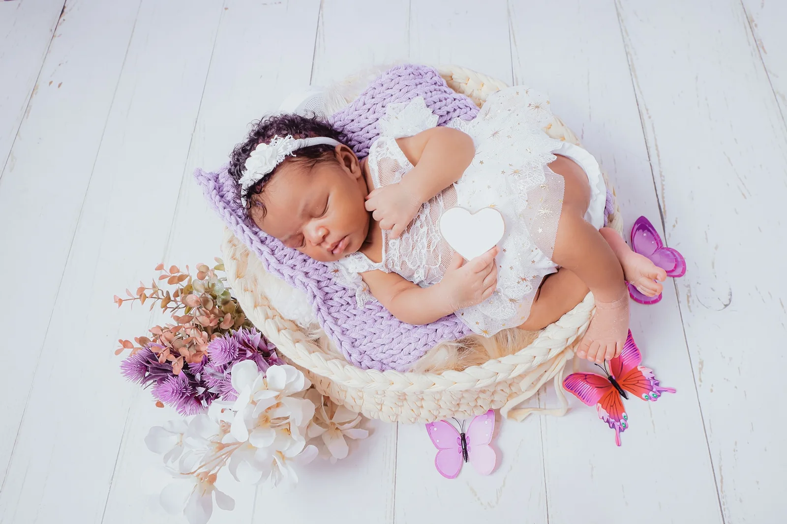 Bebê em cesta lilás durante ensaio newborn no estúdio Photos Pinnk